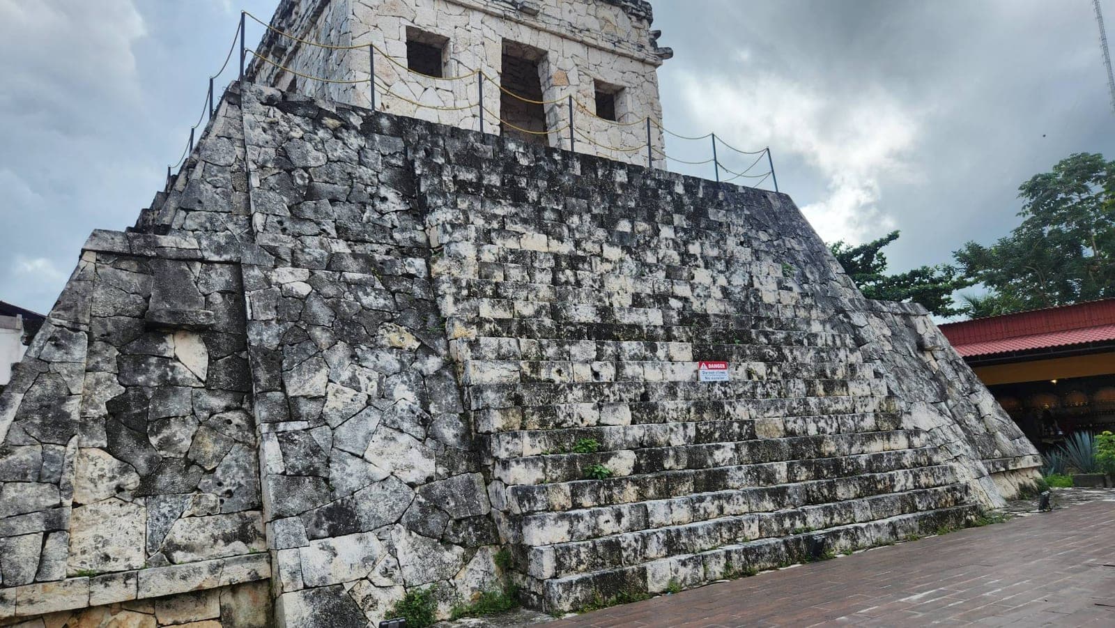 A stone Mayan pyramid structure with a 'do not climb' warning sign, visited during a Cozumel port stop