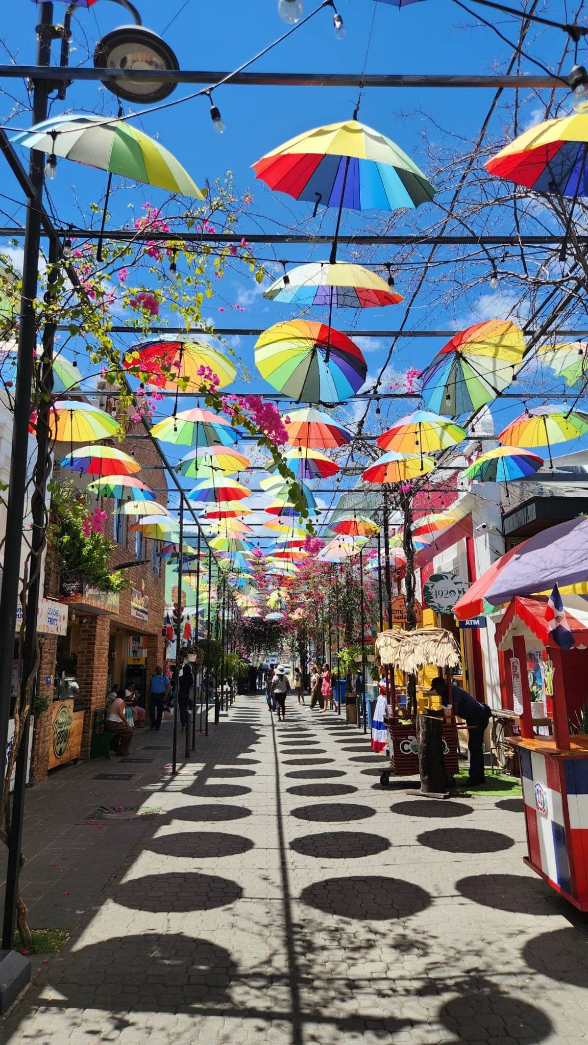 A pedestrian street in Puerto Plata covered in colorful hanging umbrellas and string lights