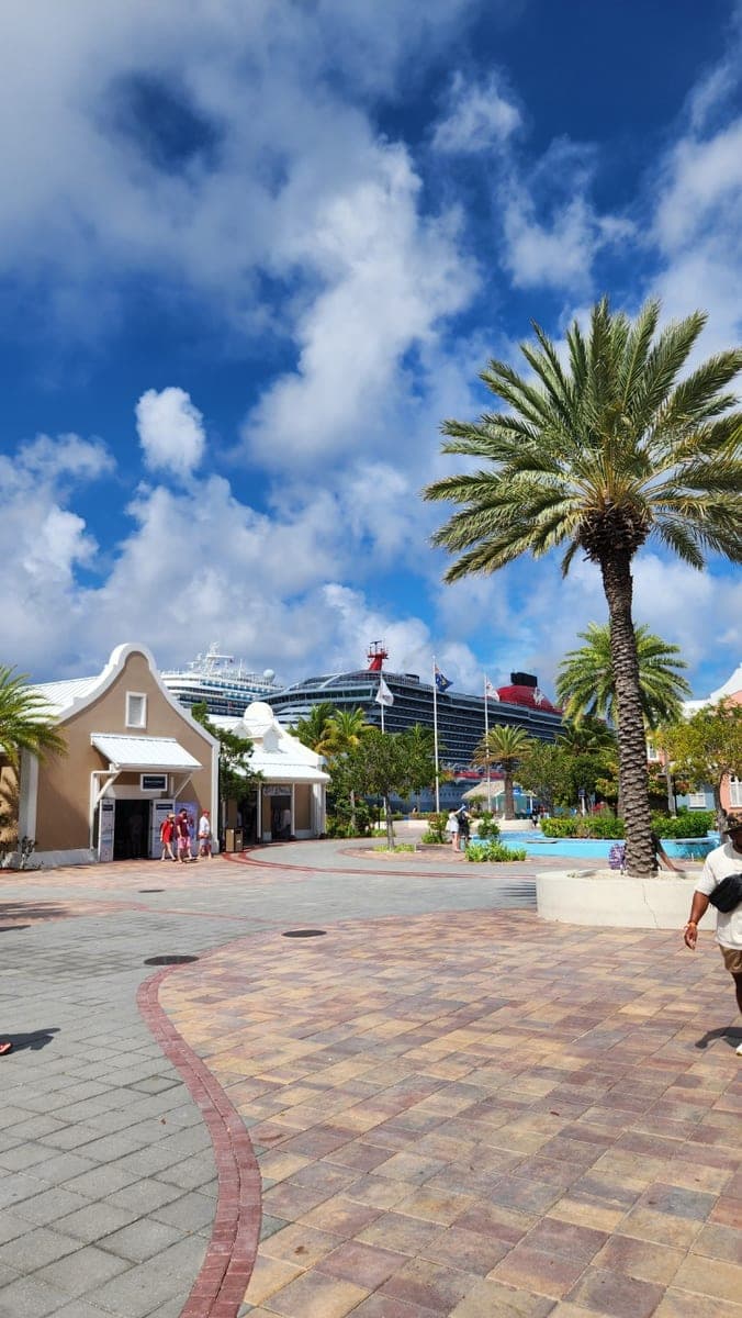 Grand Turk Cruise Center plaza with palm trees, shops, a pool, and a cruise ship in the background