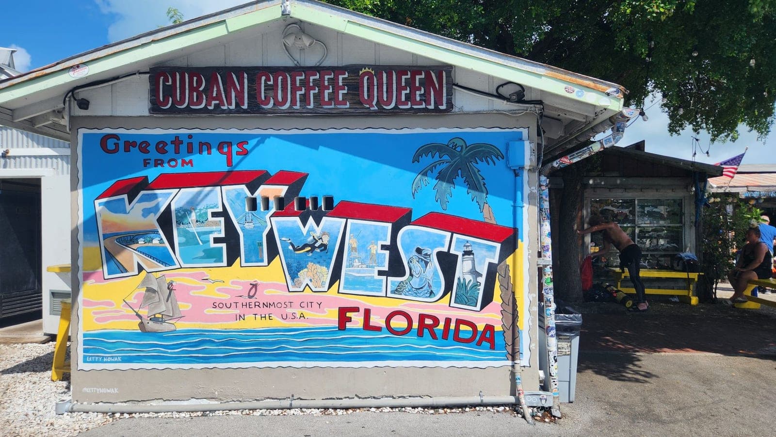 A colorful 'Greetings from Key West Florida' postcard-style mural on the Cuban Coffee Queen building