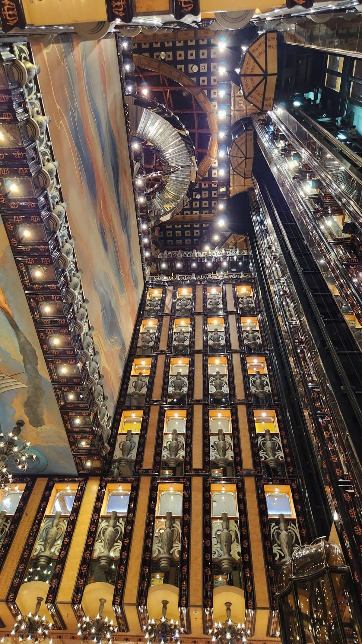 Looking down through Carnival Legend's multi-deck atrium at night, lit up around ornate balcony railings