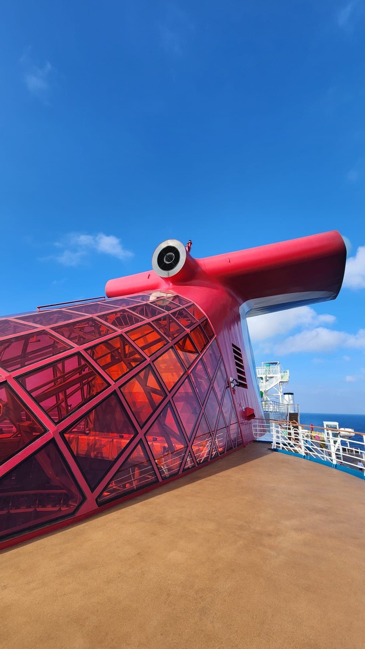 Close-up of Carnival Legend's red funnel with its glass-paneled structure against a blue sky
