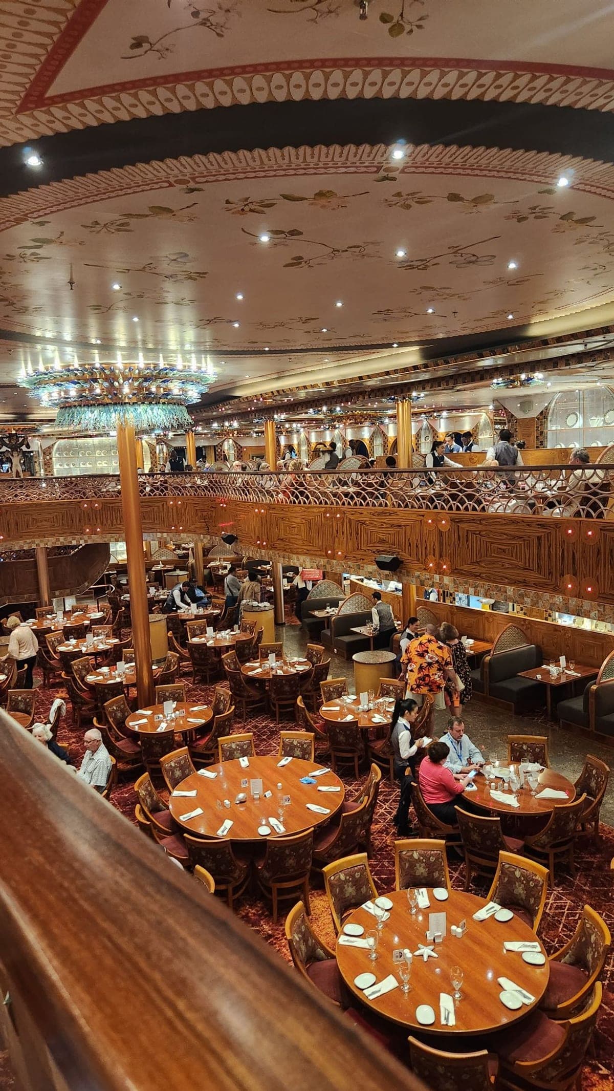 The two-level main dining room aboard Carnival Legend with an ornate painted ceiling and chandelier