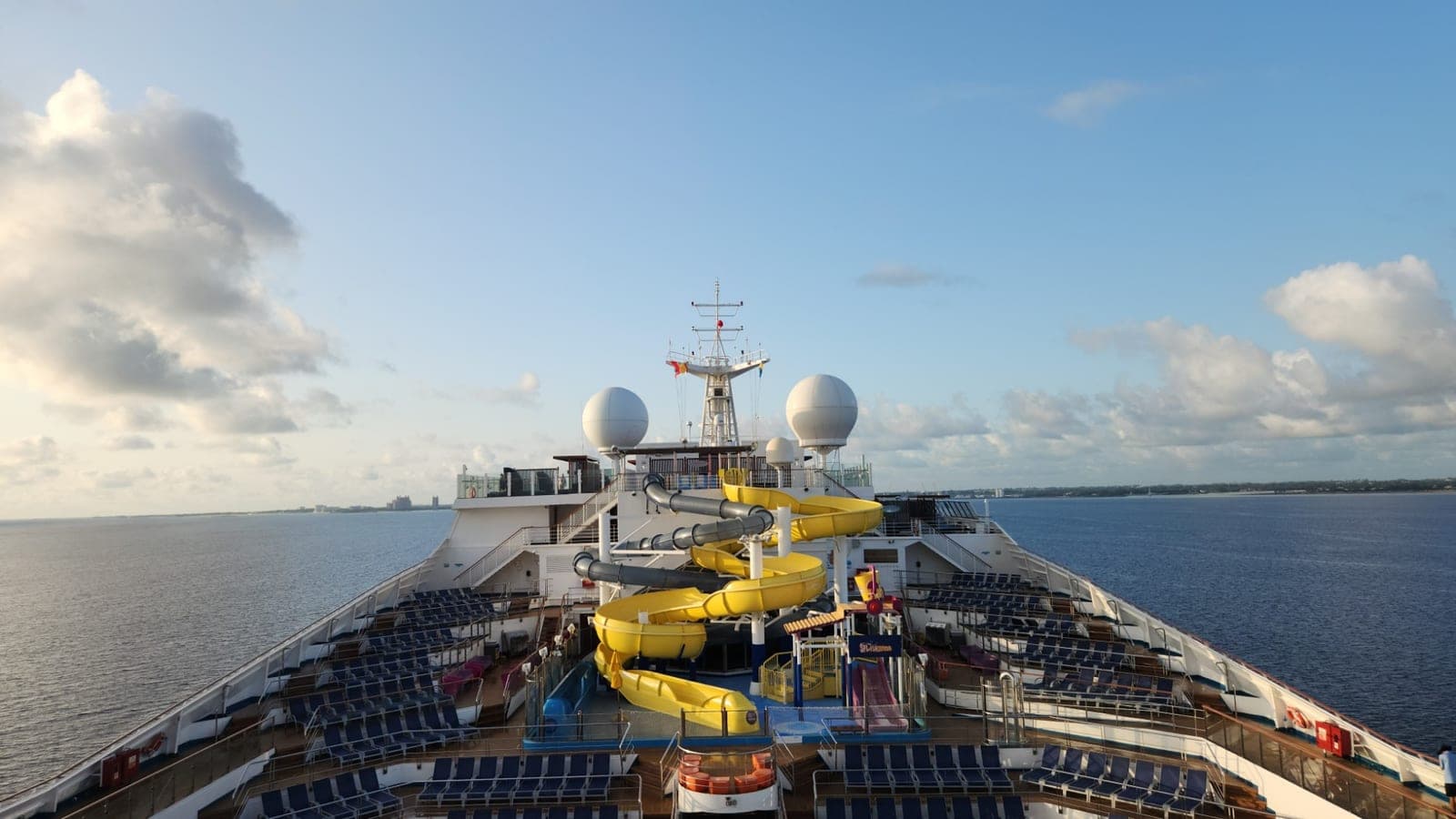 Carnival Sunrise's forward pool deck with yellow waterslides, approaching land near Nassau