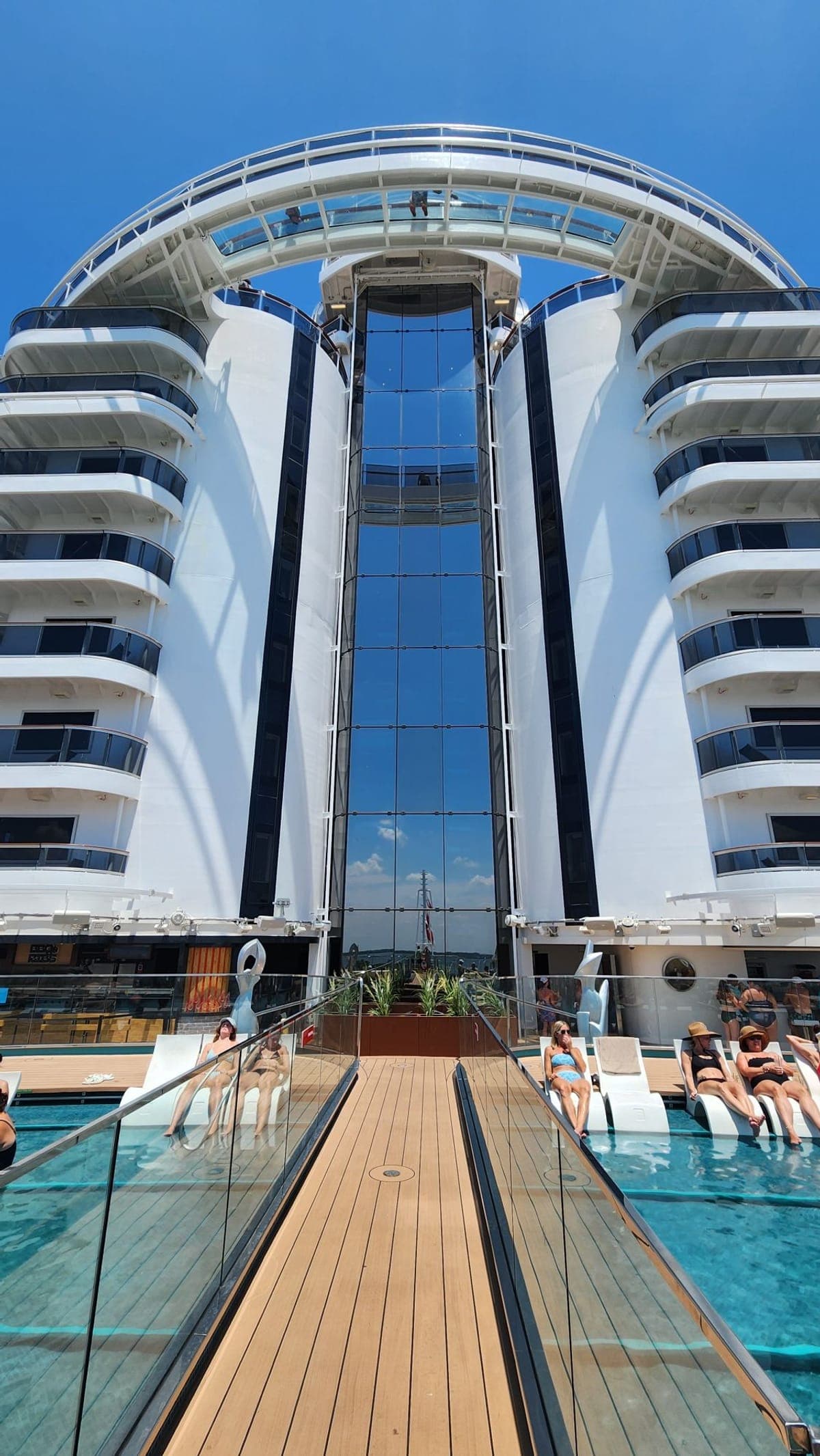 Glass-walled panoramic elevators connecting two sides of MSC Seashore's pool deck with ocean views