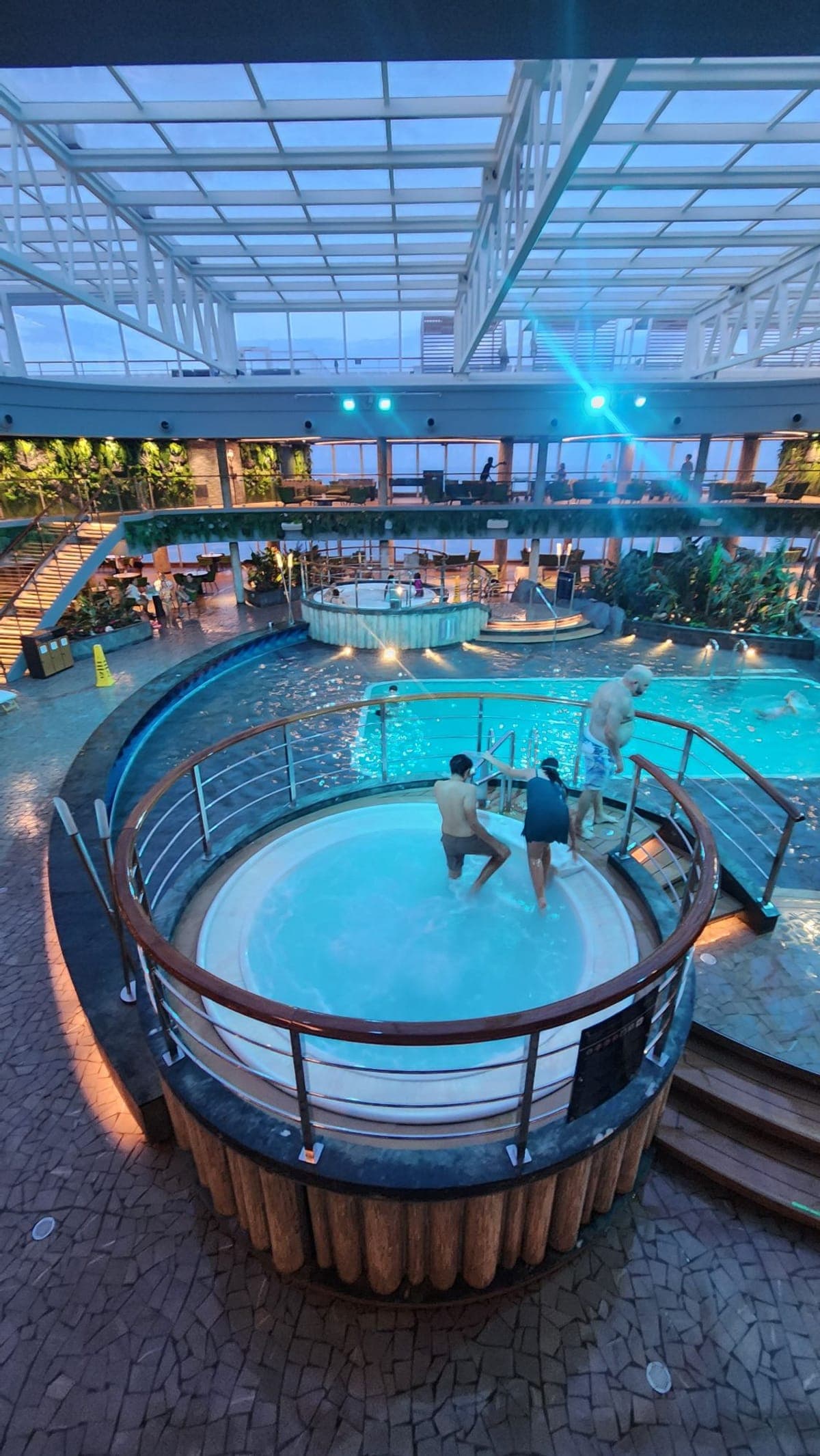 An indoor pool and hot tub area aboard MSC Seashore under a retractable glass roof at dusk