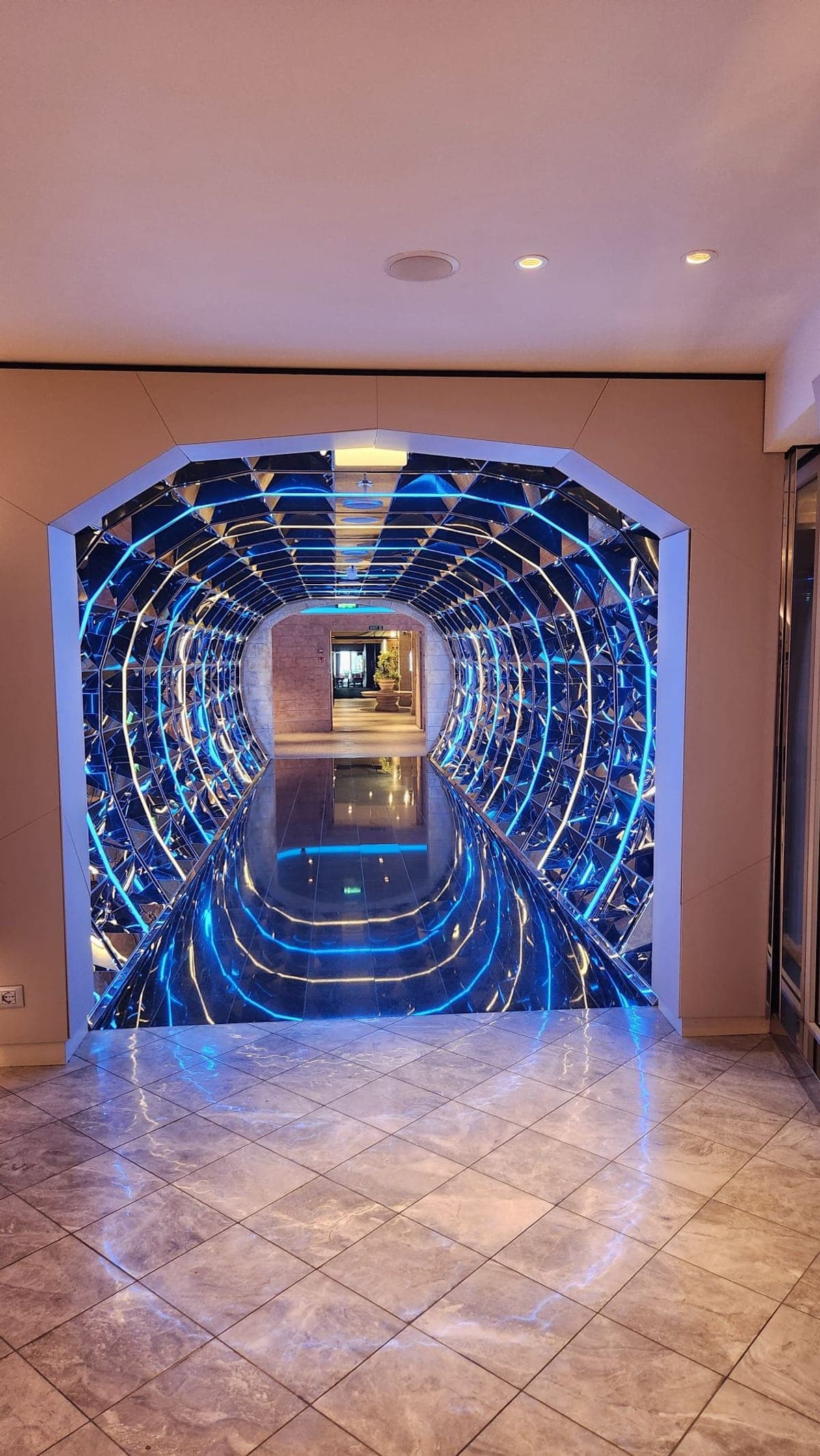 A mirrored corridor aboard MSC Seashore lit with concentric blue LED rings