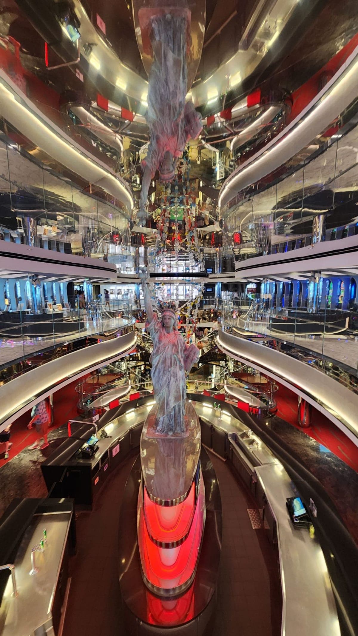 MSC Seashore's atrium with a Statue of Liberty sculpture reflected across mirrored balcony levels