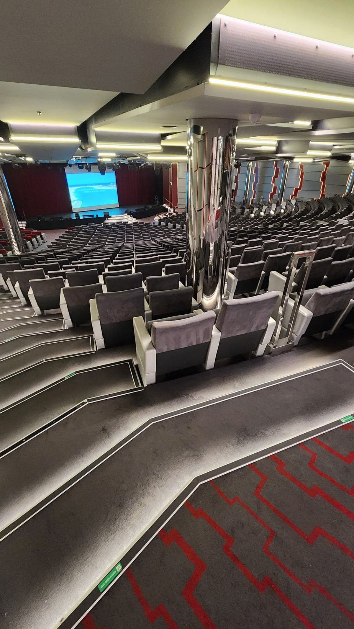 Rows of seating in MSC Seashore's main theatre, facing a stage with a large video screen