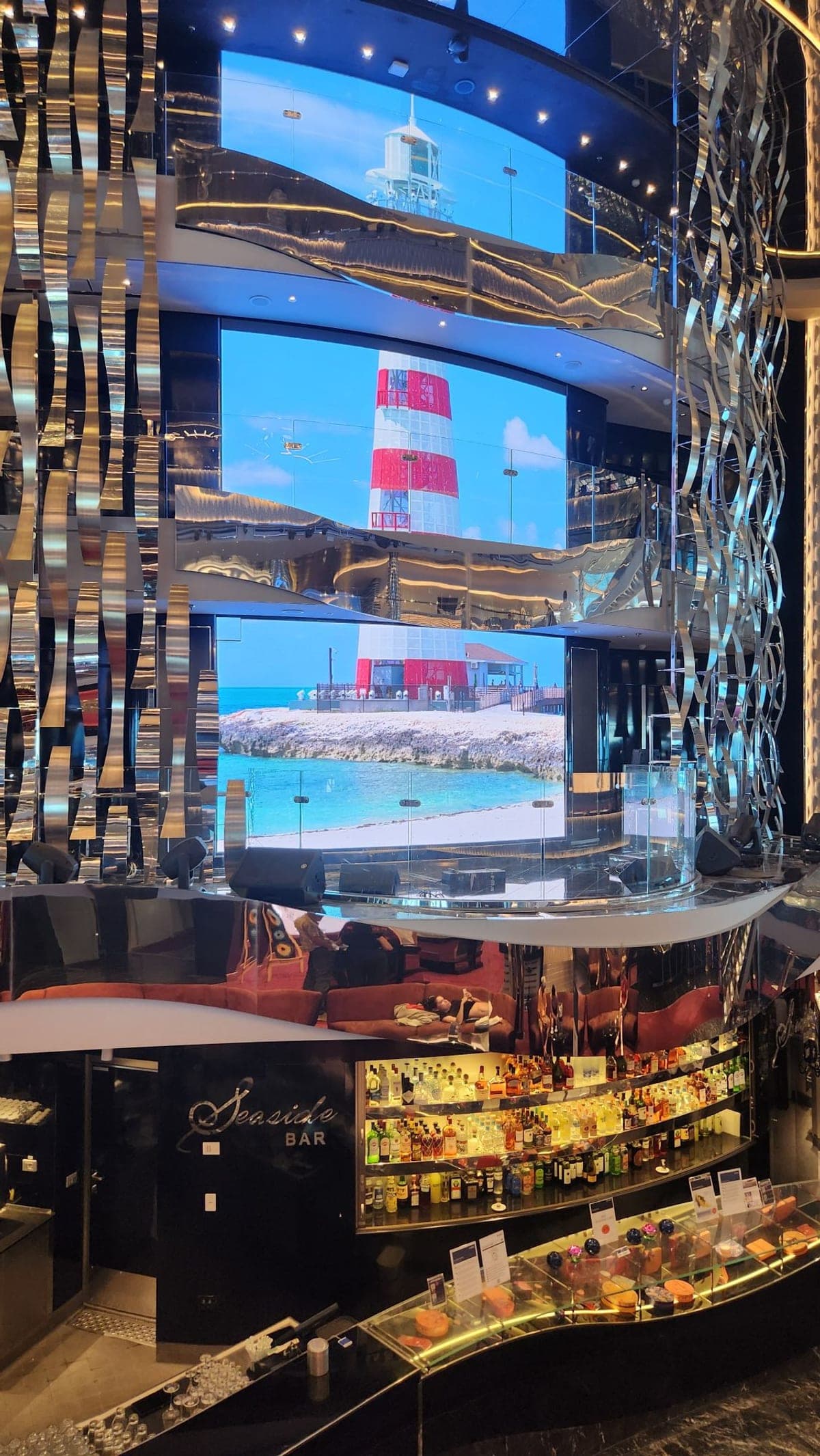 MSC Seaside's multi-deck Seaside Bar with mirrored decor and giant LED screens showing Ocean Cay's lighthouse