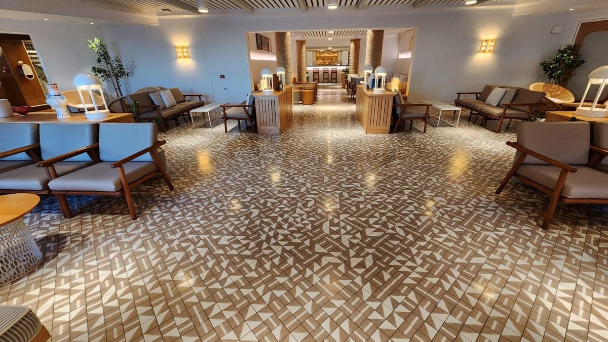 Warmly lit Resilient Lady lounge with wood furnishings, armchairs, and patterned tile flooring