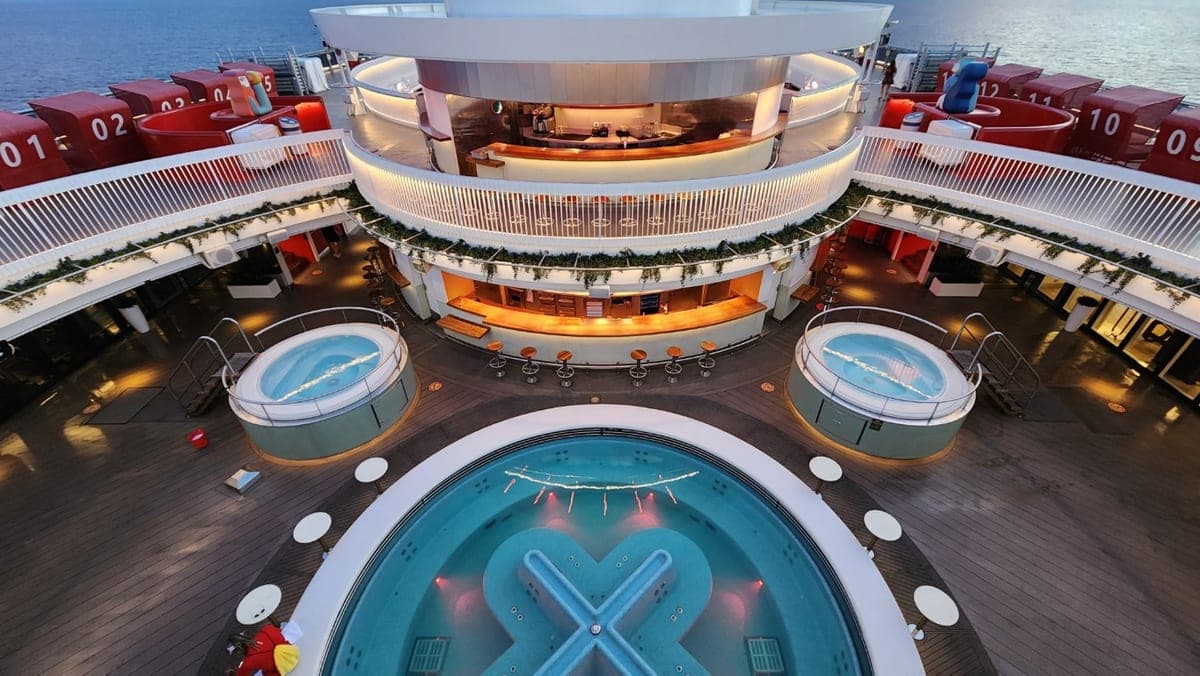 Resilient Lady pool deck with twin whirlpools, a central pool, and the open-air bar at sea